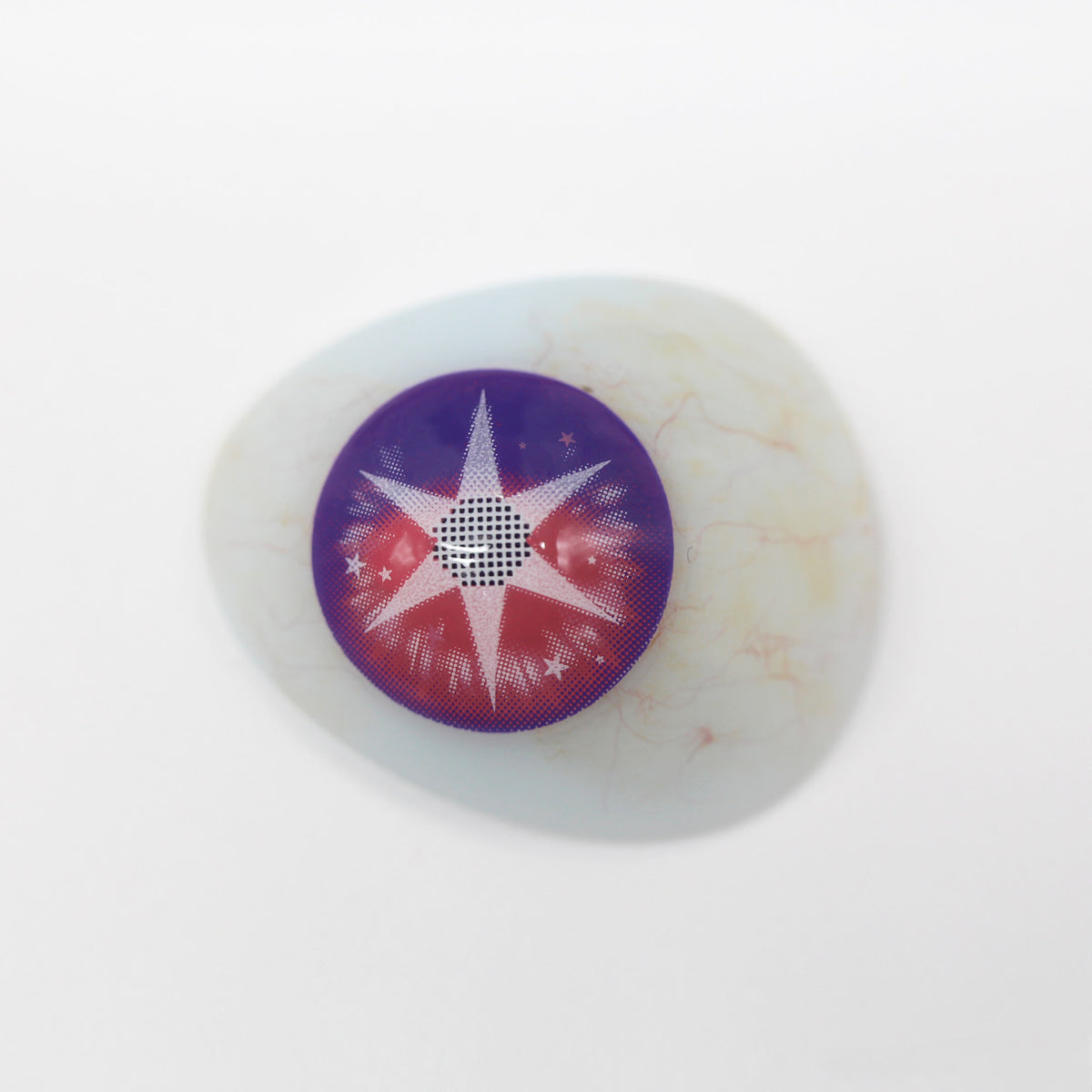 A single round contact lens with a purple outer ring, a red inner ring, and a white starburst pattern, shown on a white background.